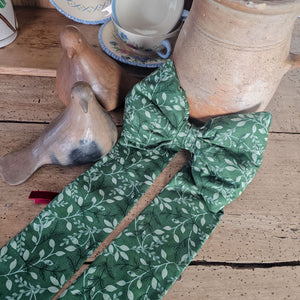 Decorative bow with festive design, brass ring, and velvet ribbon.
