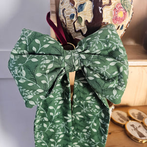 Festive bow with plush design and brass ring for Christmas tree.
