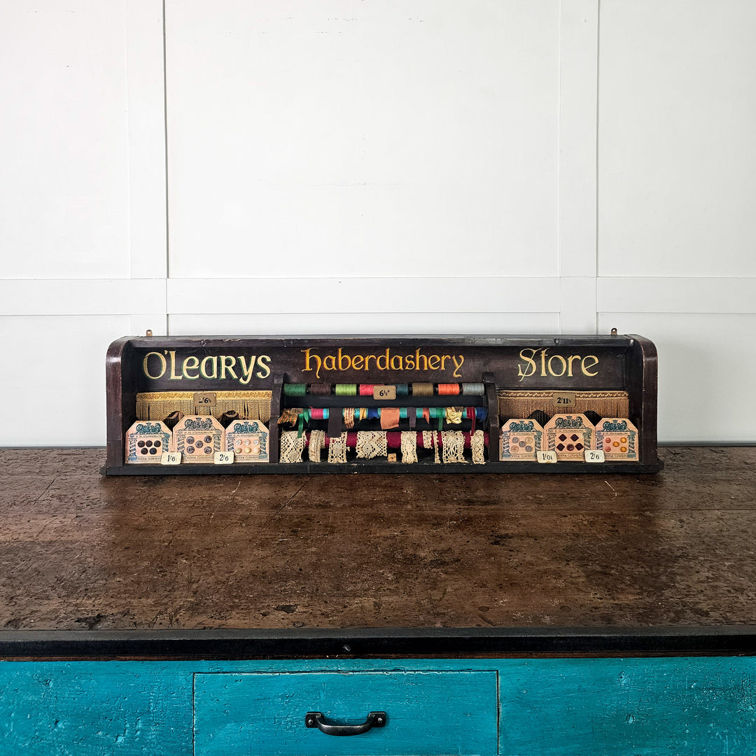 Painted wooden haberdashery display with decorative trims

