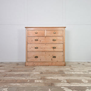 A Victorian pine chest of drawers from the 19th century with five drawers arranged in a two-over-three layout. Finished in a stripped pine finish with decorative brass handles, this five drawer storage chest works well as bedroom drawers or for storage in a hallway.