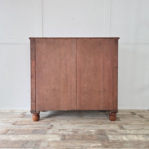 Large antique Victorian painted pine chest of drawers with authentic red finish and bun feet. Features five spacious drawers in a two over three arrangement with wooden knobs. An attractive antique storage chest for linens, clothes or household essentials.