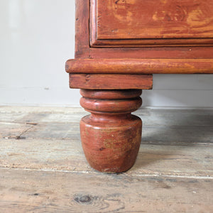 Victorian antique pine chest of drawers in red paint, with two short and three long drawers, wooden knobs and bun feet. Striking antique storage furniture for bedroom clothes, hallway household items or rustic farmhouse interiors with painted pine character.