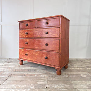 Victorian red painted pine chest of drawers with five drawers, wooden knobs and chunky bun feet. Stripped back to reveal its original finish, sealed with clear wax for protection. An antique farmhouse furniture piece perfect for bedrooms, hallways or living spaces.