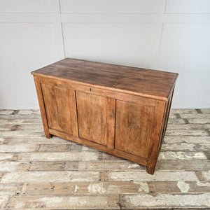 A large antique pine storage chest from the early 20th century, featuring a hinged lid, divided interior and simple block feet. The waxed pine surface highlights its cottage and farmhouse style, making it a robust wooden trunk for storing linens or household items.