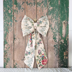 Handmade floral bow from vintage fabric, displayed on an aged wooden door