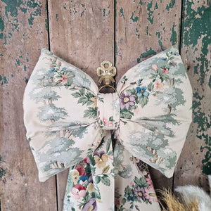 "Elegant floral bow with removable brass ring and velvet ribbon for hanging.