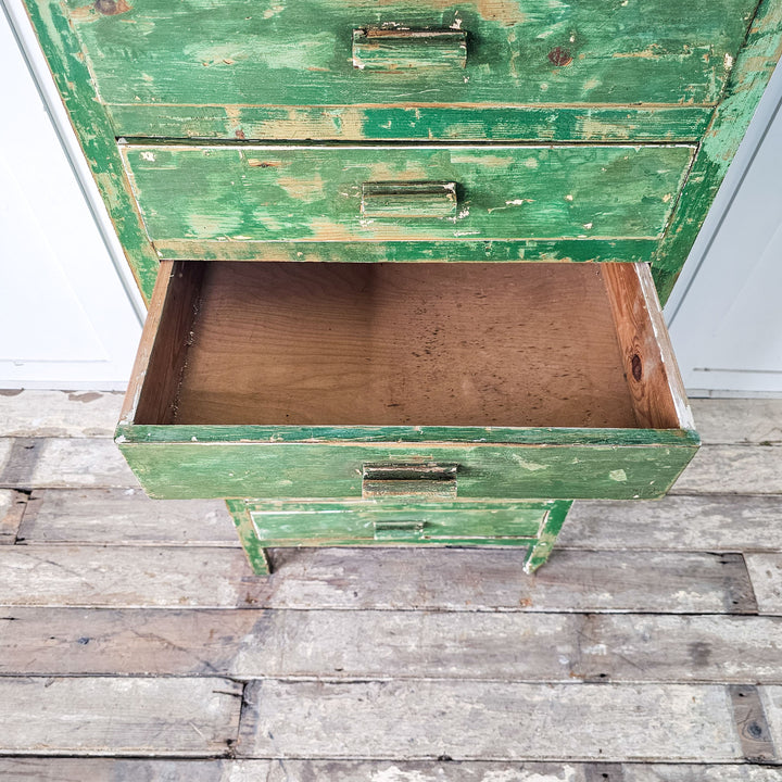 Retro storage unit: A charming cabinet from the 1930s, painted green and adorned with wooden handles on each of its eight drawers