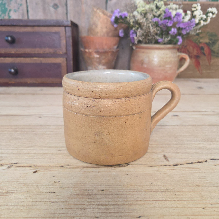 A vintage French stoneware pot with rounded body, sturdy handle, and glazed finish in natural tones. Sometimes called a confit or rillette pot, this traditional French kitchen jar is ideal for utensil storage or displaying herbs and small plants.