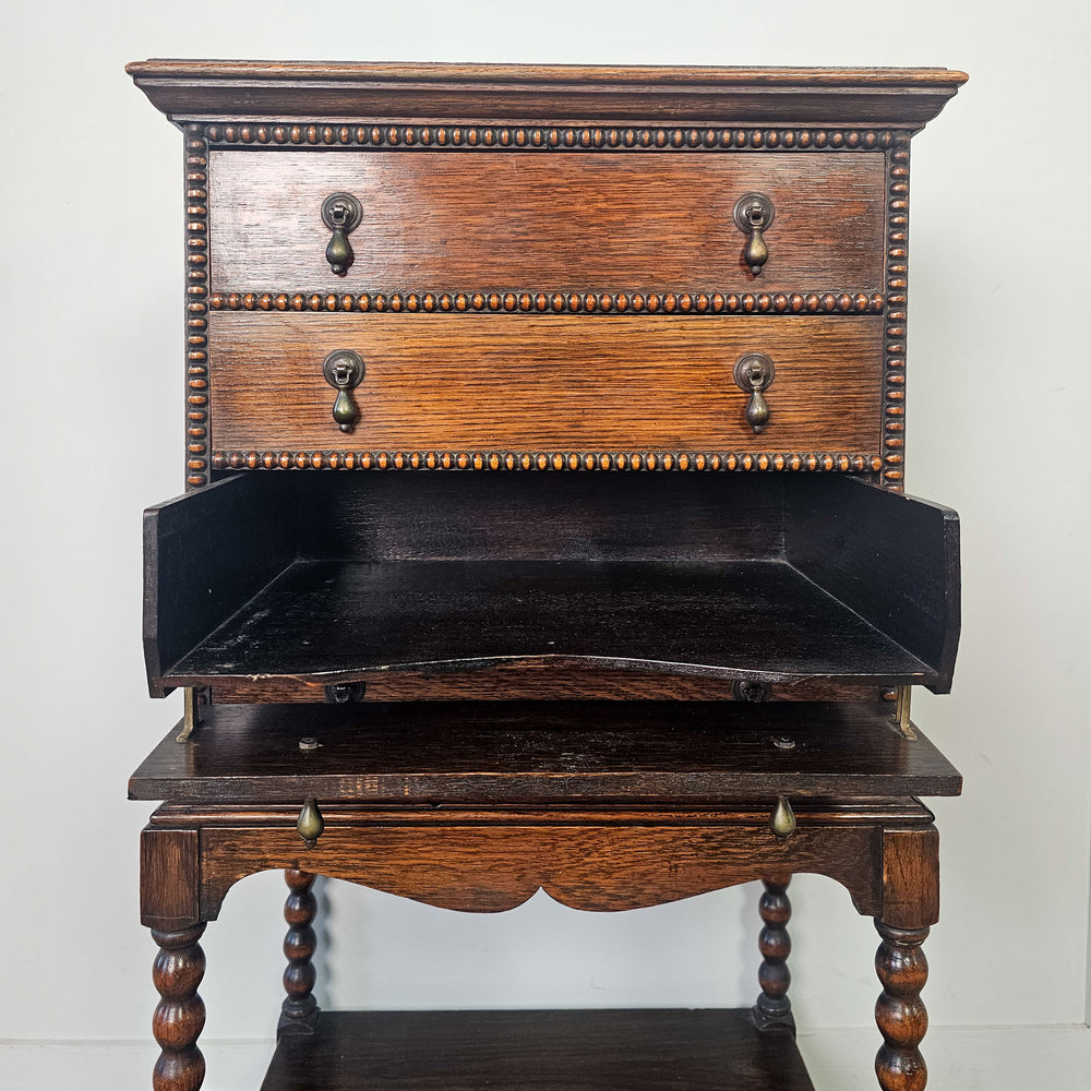 Oak cabinet with sliding drawers and bobbin legs.
