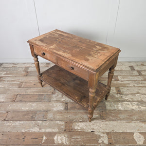 An antique Victorian farmhouse painted pine hall table featuring two drawers with wooden knobs and four turned legs. The table includes a lower shelf beneath for additional storage and retains its original painted pine finish across the frame.

