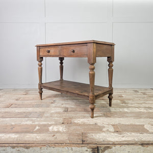 A 19th century Victorian country painted pine side table with two drawers fitted with wooden knobs and supported by four turned legs. The table includes a lower shelf below and retains its original painted pine finish.
