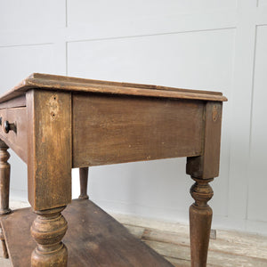 An antique rustic painted pine console table dating to the Victorian period, featuring two drawers with turned wooden knobs and four turned legs. The table incorporates a lower shelf beneath and retains its original painted surface throughout.
