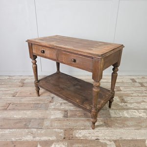 A Victorian farmhouse painted pine hall table with two drawers to the front fitted with wooden knobs. Raised on four turned legs, the table includes a lower shelf below and retains its original painted finish from the 19th century.
