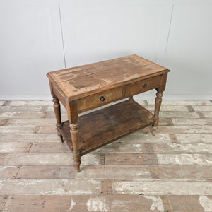 A 19th century antique country painted pine side table featuring two drawers with wooden knobs and supported by turned legs. The table incorporates a lower shelf beneath and retains its original painted pine surface.

