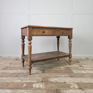 An antique Victorian rustic painted pine console table from the 19th century, with two drawers fitted with wooden knobs and raised on four turned legs. The table includes a lower shelf beneath and retains its original painted finish throughout the piece.
