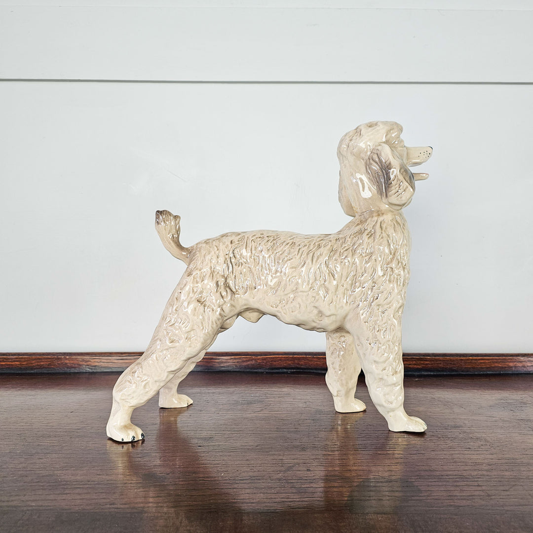 A side view of a vintage ceramic poodle with grey and white coat with glazed finish