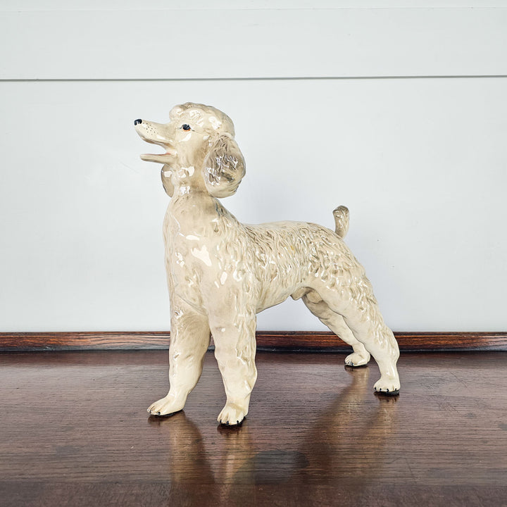 A side and angled view of a ceramic grey and white poodle figurine showing the fur texture