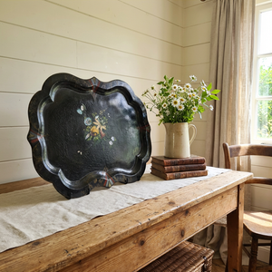 A large Victorian papier-mâché black serving tray dating from the mid to late 19th century, with a black lacquered finish, painted decorative details, and a handpainted floral bouquet to the centre with mother of pearl inlay. Originally used for serving tea or drinks, it now works well displayed on a table, placed on a stand, or used as wall décor.