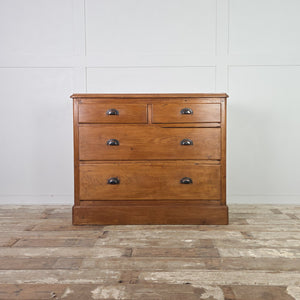 Rustic antique pine chest of drawers with four drawers in a two-over-two arrangement, later-added cup handles, and a plain plinth base, sealed with pine wax to protect the surface.

