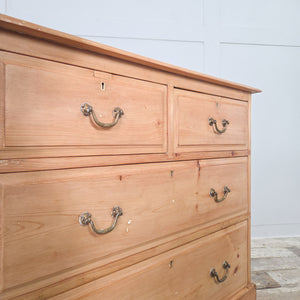 This four drawer antique pine chest of drawers dates from the early 20th century and features a two-over-two drawer layout, brass swan-neck swing handles and a plinth base with shaped cut-out. A useful storage piece for use in the bedroom or positioned in a hallway or landing for additional drawer storage.