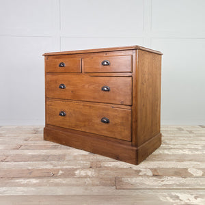 Rustic pine chest of drawers from the early 20th century, offering four drawers for storage, raised on a simple plinth base and sealed with a protective pine wax finish.
