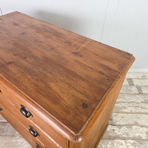 Early 20th century pine chest of drawers with four deep drawers, later-added cup handles, and a simple plinth base supporting the piece.
