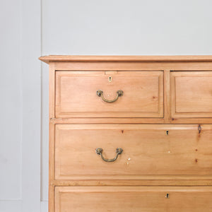 A four drawer antique pine chest of drawers dating from the early 20th century, featuring a two-over-two drawer layout, brass swan-neck swing handles and a plinth base with decorative cut-out. Well suited to bedroom storage, or positioned in a hallway or landing for everyday use.