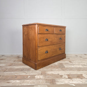 Four-drawer pine chest of drawers dating to the early 20th century, with later-added cup handles and a simple plinth base beneath.
