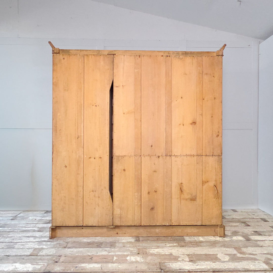 19th century Victorian pine wardrobe with a mirrored centre door, two side doors, and internal drawers. This antique pine triple wardrobe provides hanging space, drawers, and a storage compartment within a classic Victorian design. A solid and functional example of antique pine furniture and practical bedroom storage.