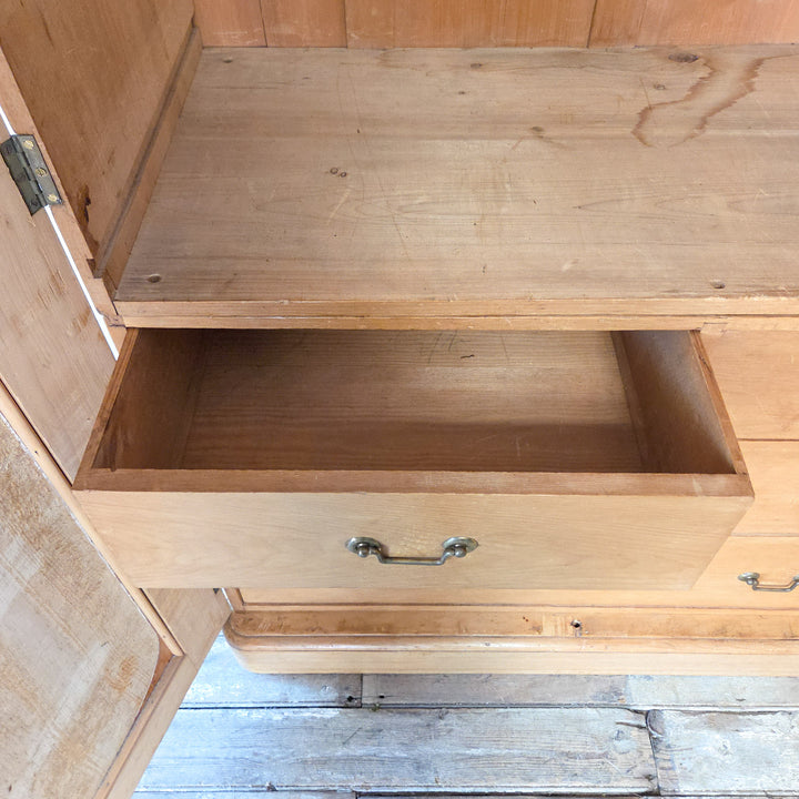 19th century Victorian pine triple wardrobe with mirrored door, brass handles, and glass knobs. The interior layout includes drawers, rails, and compartments, making it both practical and decorative. A solid antique pine wardrobe typical of late Victorian bedroom furniture.