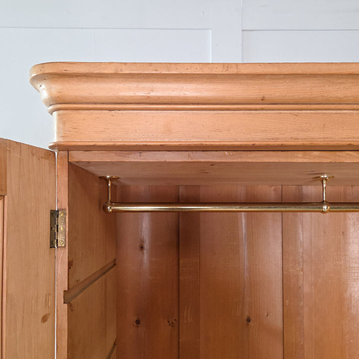 Antique Victorian pine wardrobe with triple doors and mirrored centre, dating to the 19th century. Constructed from solid pine with brass and glass fittings, this wardrobe offers a combination of drawers, rails, and compartments, typical of quality Victorian furniture.