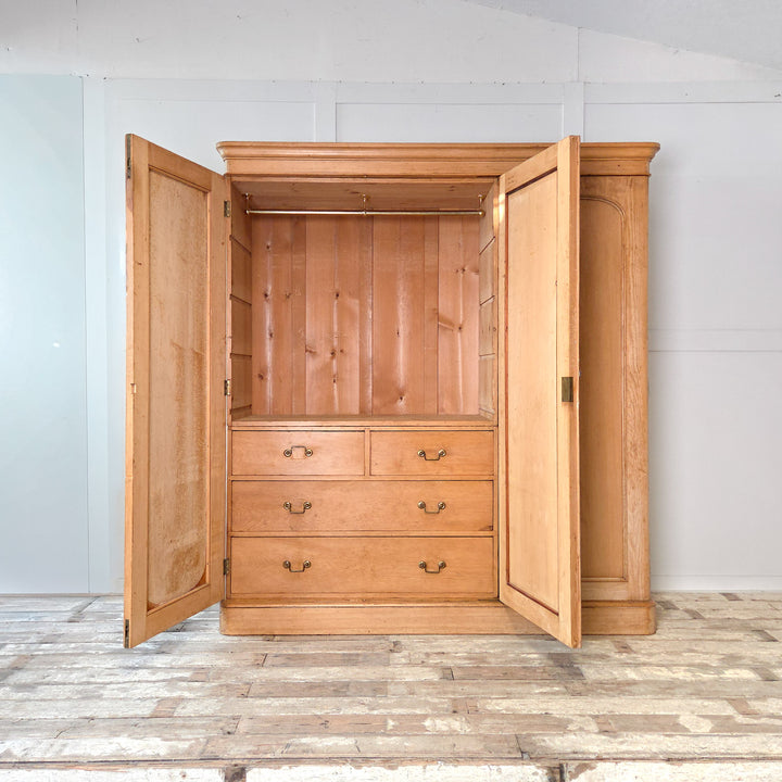Victorian pine triple wardrobe with mirrored door, drawers, and hanging rails. This late 19th century pine wardrobe features a concealed compartment and brass fittings, representing a classic example of antique pine bedroom storage and Victorian craftsmanship.