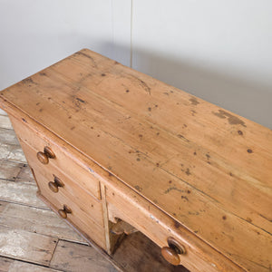 A Victorian pine dresser base with seven drawers in graduating depths and a central open shelving section. Original turned wooden knobs are fitted throughout, and the piece can be used as a kitchen dresser base or as a sideboard in a living space.