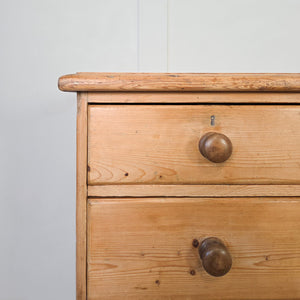 A rustic Victorian pine dresser base with seven drawers flanking a central open shelving section. Raised on bun feet, the piece can be used as a kitchen dresser base or placed in a living space as a sideboard.
