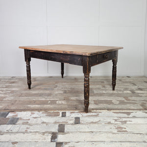 This 19th century farmhouse table features a solid planked beech top set over a painted base with turned legs. The original black paint shows gentle wear, while two drawers, one at each end, provide useful storage for everyday items.