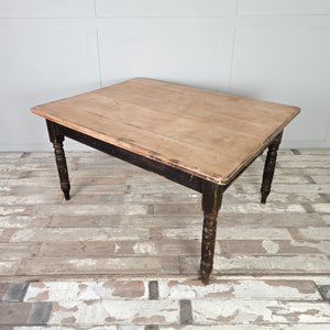 A 19th century farmhouse dining table with a planked hardwood top, likely beech, supported by a painted base with turned legs. The original black paint remains intact, and the moulded edge of the top gives the table a defined, finished outline.