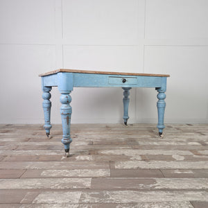 A Victorian pine farmhouse table from the 19th century with a scrubbed natural top and painted powder blue base. The table has a single drawer and castors and works well as a kitchen table for everyday use.
