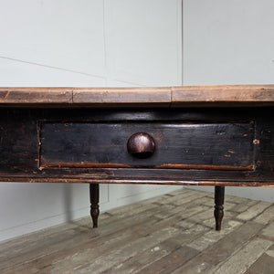 This 19th century farmhouse dining table features a planked beech top over a painted base with turned legs. The original black paint remains to the base, and two end drawers with wooden knobs provide useful storage, making it ideal as a family dining table or kitchen table.