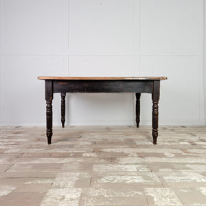 This antique farmhouse table dates from the 19th century and has a planked beech top over a black painted base. Raised on four turned legs, it includes two drawers and is well suited as a dining table or work table in a kitchen setting.