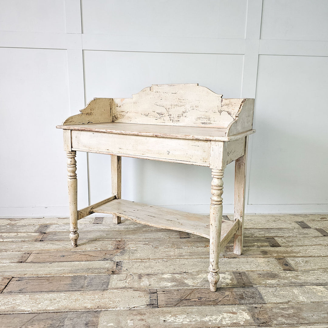 A vintage 19th-century English pine washstand with distressed white paint finish.