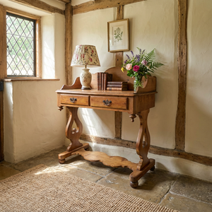 A rustic farmhouse-style antique Victorian pine washstand from the late 19th century, featuring a shaped gallery back, two drawers with brass swan neck handles and a lower shelf. The pine is sealed in antique wax and the washstand stands on shaped supports with ball feet.