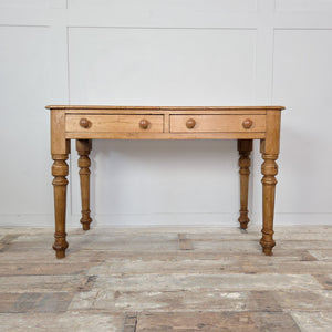 A 19th-century pine desk or console table with two drawers and turned legs. The waxed finish enhances the natural patina, ideal for farmhouse or country-style interiors.