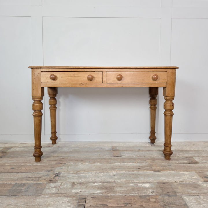 A 19th-century pine desk or console table with two drawers and turned legs. The waxed finish enhances the natural patina, ideal for farmhouse or country-style interiors.