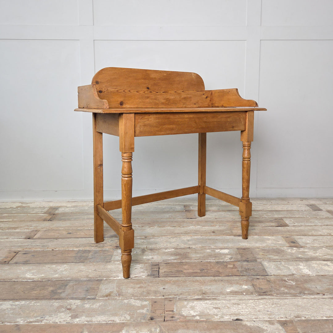 Antique Victorian washstand crafted in pine with a gallery back and turned legs. The waxed surface enhances the warm natural tone, making this 19th-century piece ideal as a side or dressing table in a country or farmhouse style interior.