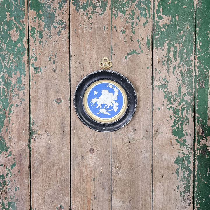 Decorative wall plaque with cherubs and gold accents.
