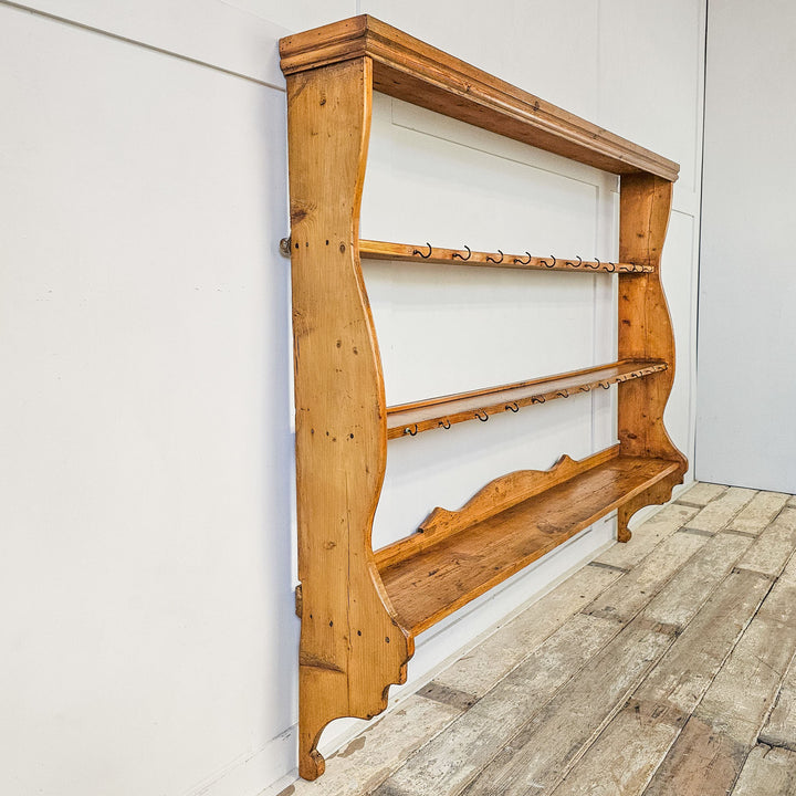 Antique pine wall rack displaying plates and cups.