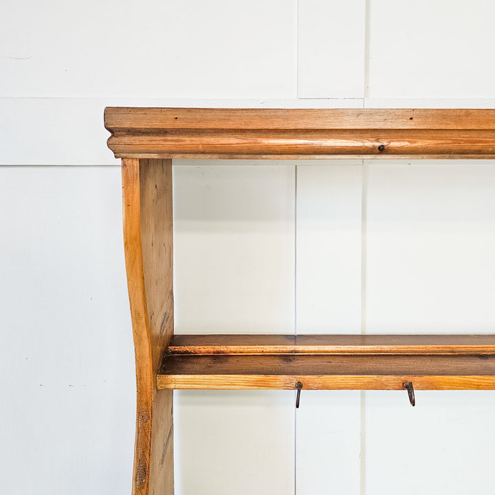 Rustic pine wall rack with three shelves for plates.