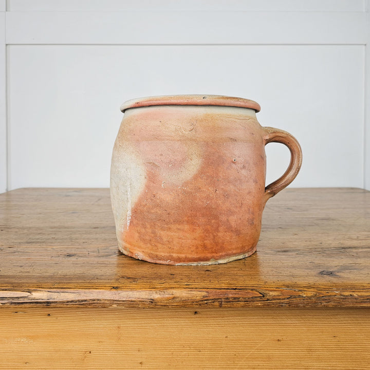 Decorative antique rillette pot with a handle for easy transport.