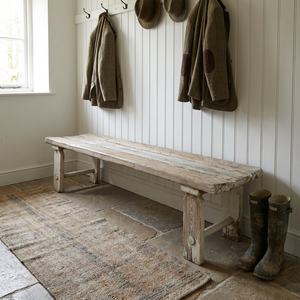 An early 20th-century rustic pine bench with a three-plank top and straight legs joined by circular lower stretchers. This vintage country bench can be used in a hallway or boot room, at the foot of a bed, or as a simple dining bench in a kitchen.