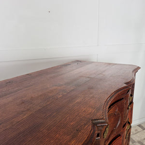 Antique French walnut serpentine chest of drawers dating to the 19th century. Four carved drawers with ornate brass handles and escutcheons define the piece, which is raised on carved legs and finished with the warm tones of aged walnut.